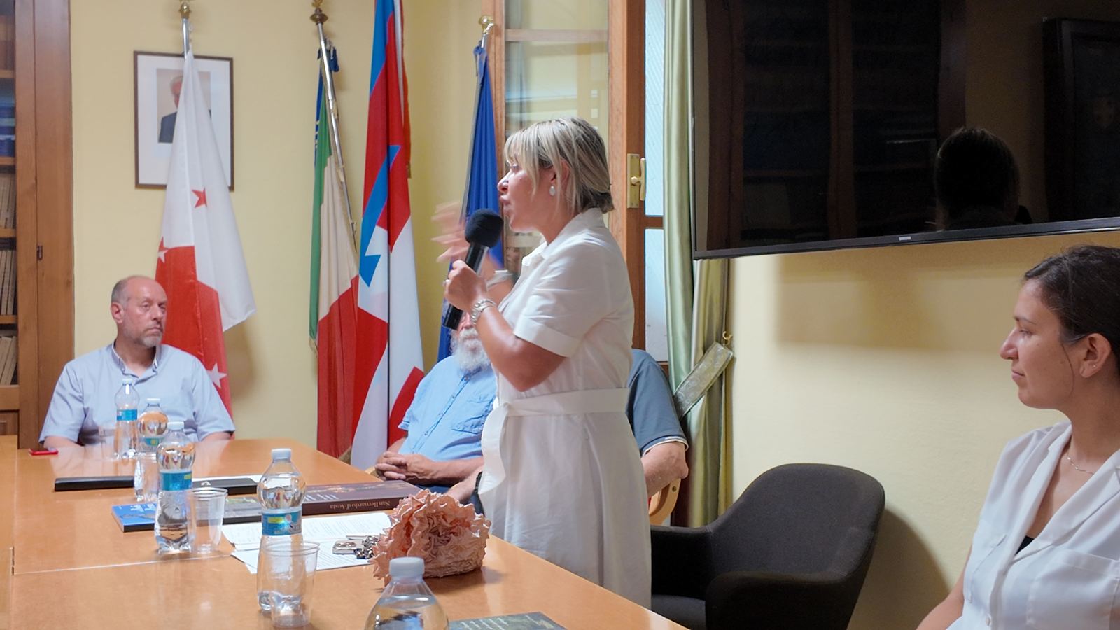Relatrice in piedi accanto al tavolo della Sala consiliare