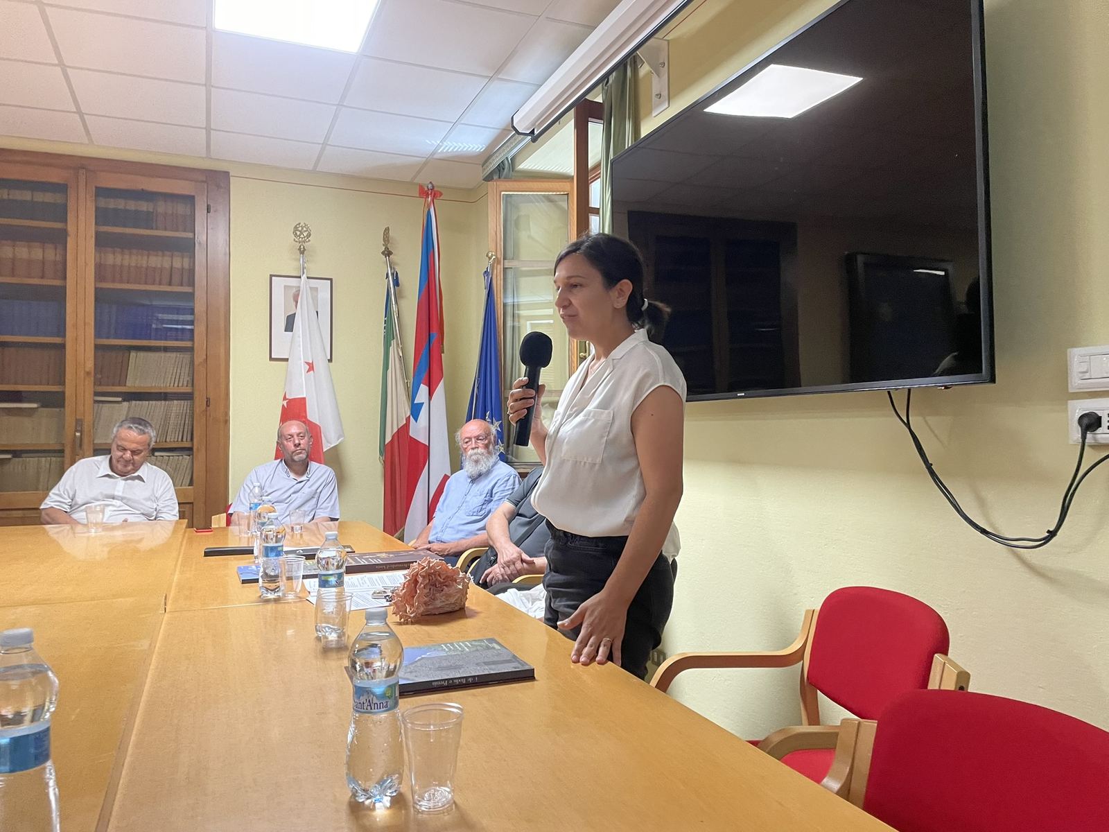 Relatrice con il microfono al tavolo dell’incontro istituzionale