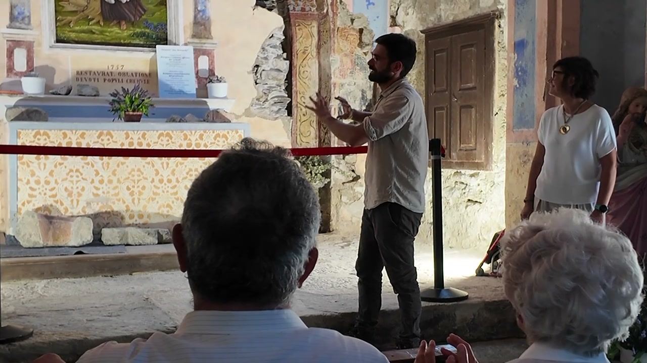Due persone illustrano il restauro ai visitatori, accanto agli affreschi